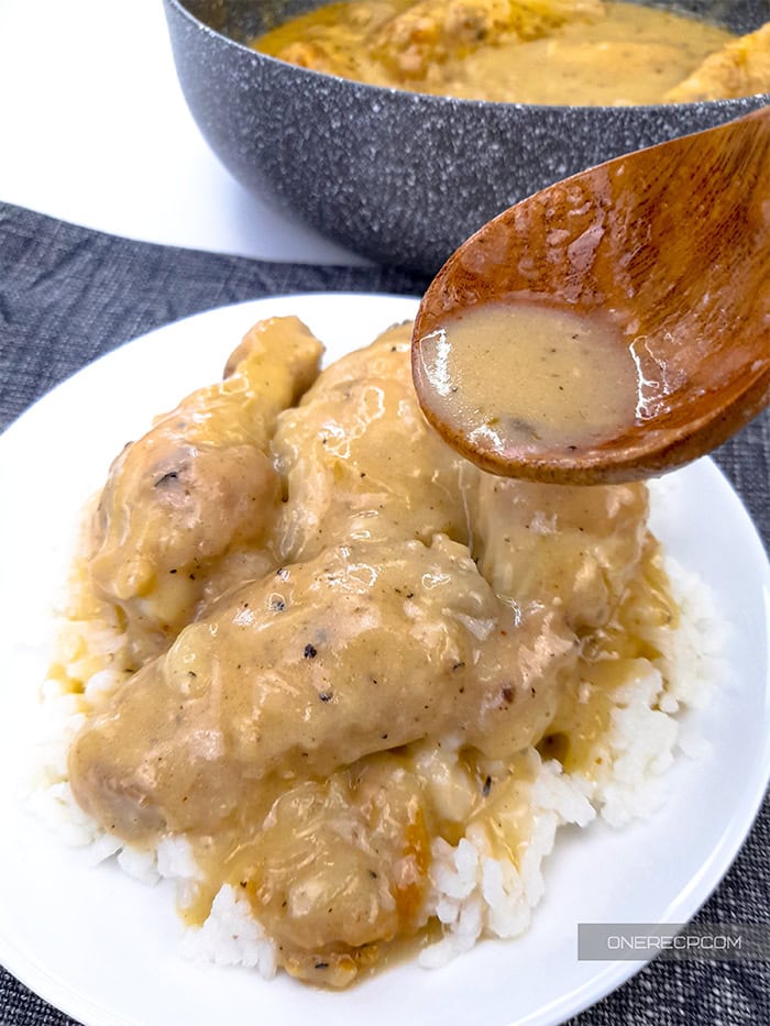 A serving of smothered chicken wings over a bed of rice