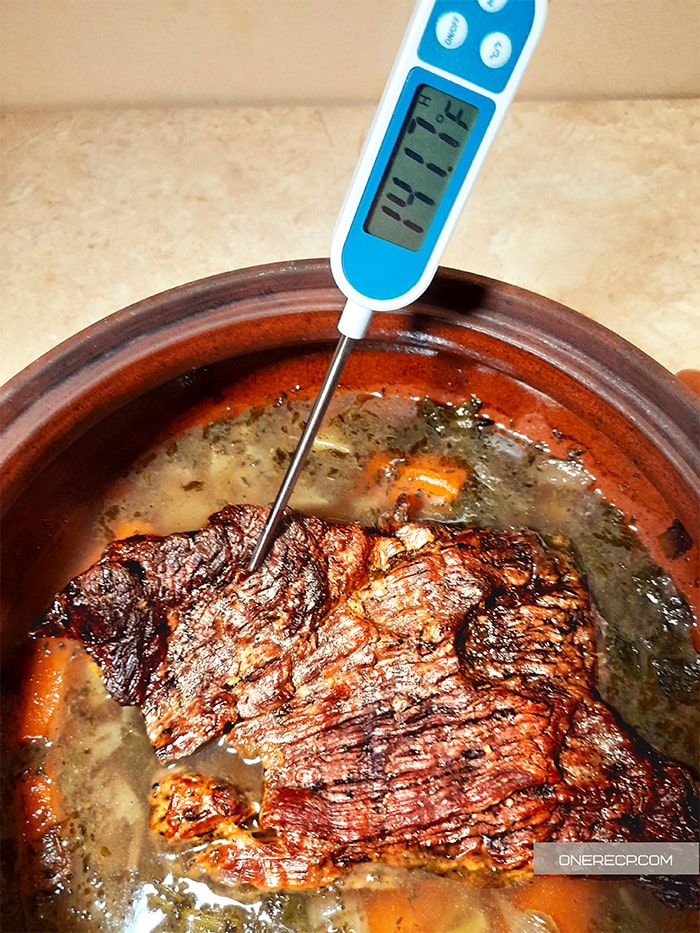 Testing the temperature of a beef roast in a pot with a meat thermometer