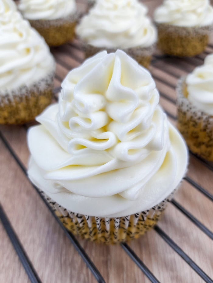 a close view of a vanilla frosting cupcake on a baking rack