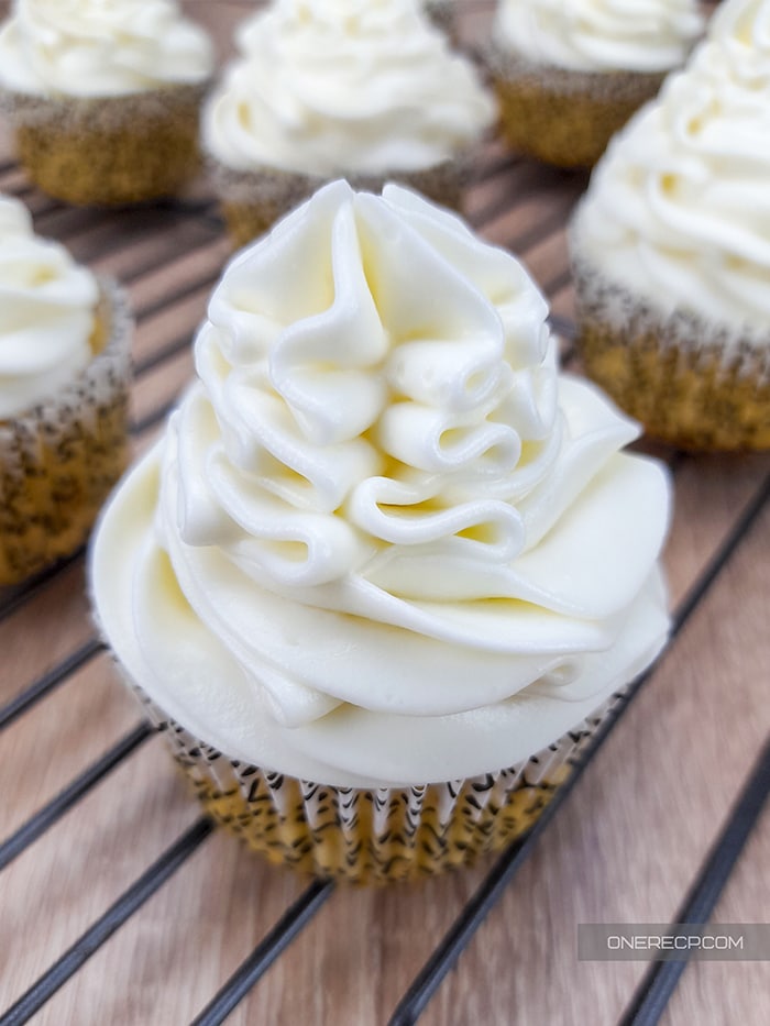 a rack of cupcakes with fluffy vanilla frosting on top 