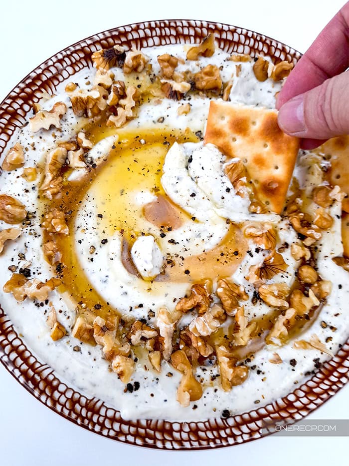 Dipping cracker into whipped feta cheese.